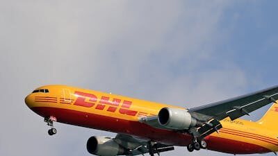 pexels photo 20016279 20016279 A DHL cargo airplane flying high against a clear blue sky, showcasing logistics and air transport.
